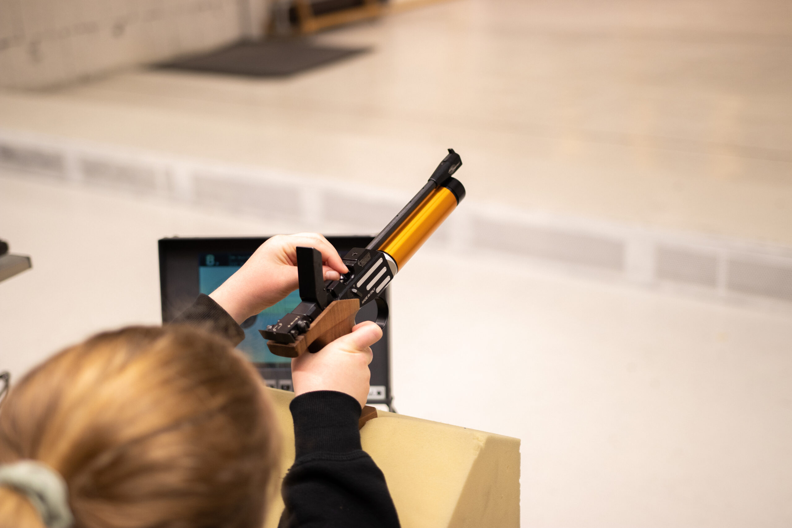Hånd som holder en pistol på en innendørs pistolbane. Foto.